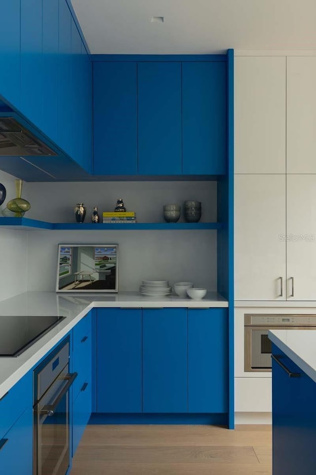 kitchen with blue cabinets, oven, light wood-style floors, and black electric cooktop