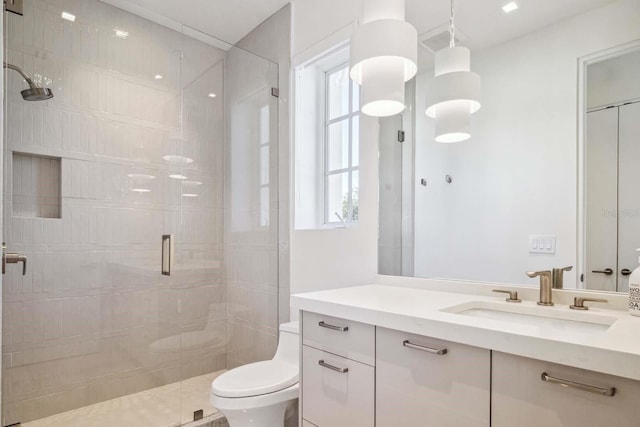 bathroom featuring toilet, a healthy amount of sunlight, vanity, and a stall shower