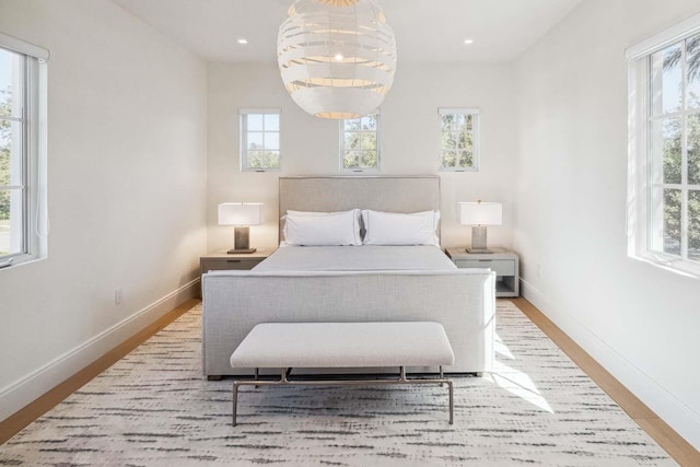 bedroom featuring baseboards, wood finished floors, and multiple windows