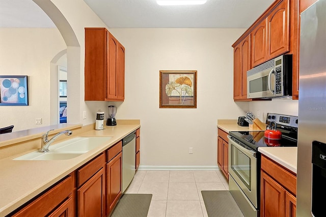 kitchen featuring light countertops, appliances with stainless steel finishes, light tile patterned floors, and a sink