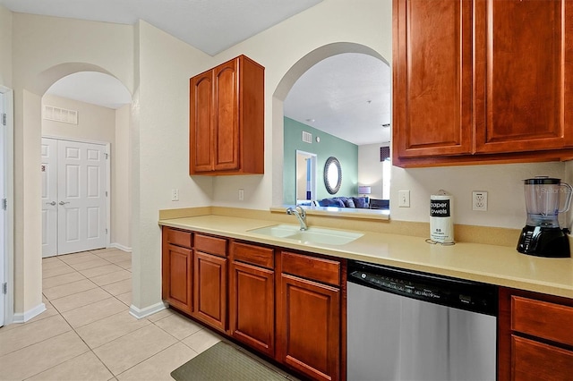 kitchen featuring light countertops, arched walkways, a sink, dishwasher, and light tile patterned floors