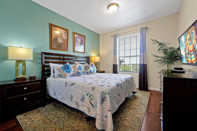 bedroom featuring baseboards and dark wood-type flooring