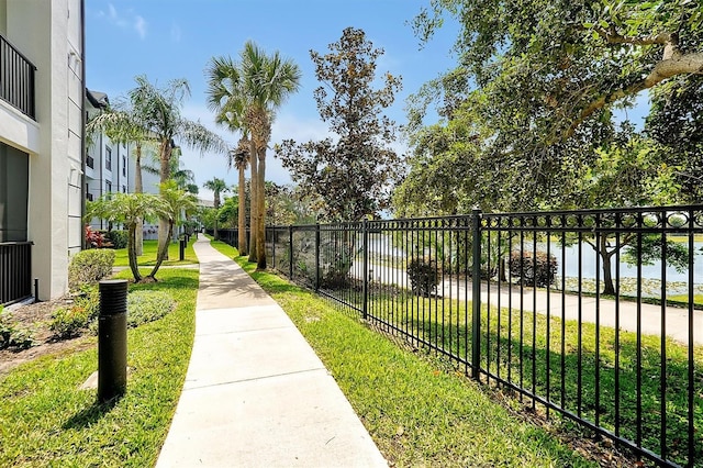 view of home's community featuring fence, a lawn, and a water view
