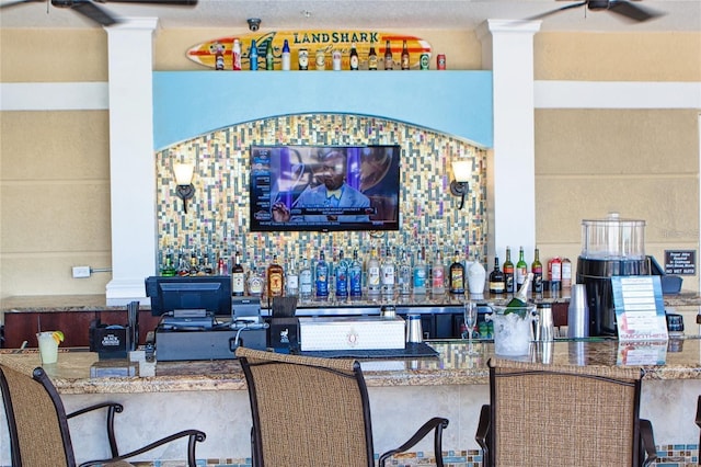bar with a ceiling fan, ornate columns, and a community bar
