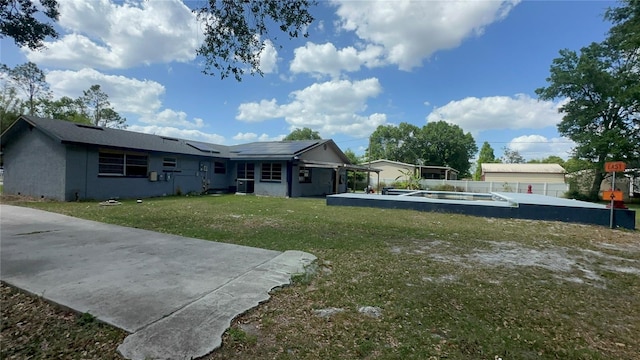 434 Diamond Acres Rd, Davenport, FL 33837 - rear view of property with a lawn, solar panels, and fence