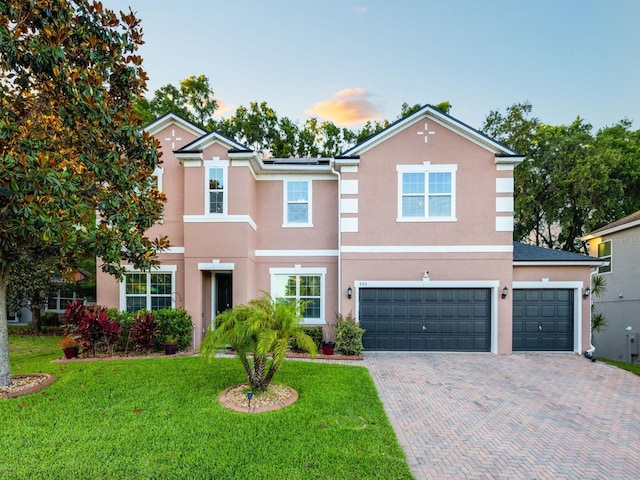 view of front of property featuring a front lawn, stucco siding, decorative driveway, and a garage