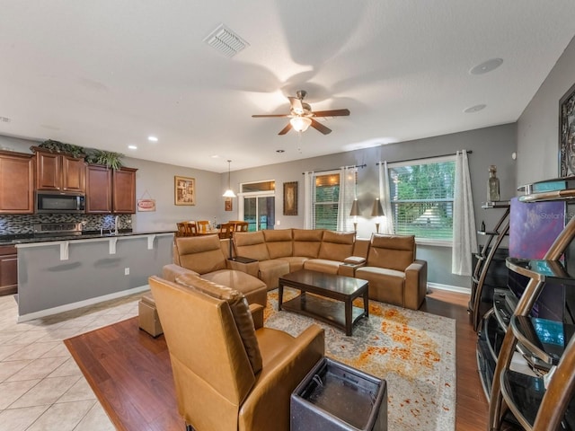 living room with light tile patterned floors, visible vents, baseboards, ceiling fan, and recessed lighting