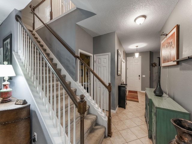 entrance foyer featuring stairway, a textured ceiling, and light tile patterned flooring