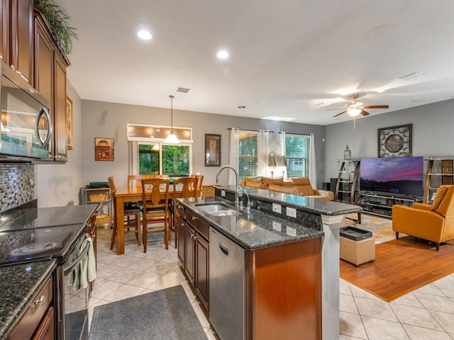 kitchen with a sink, visible vents, open floor plan, light tile patterned floors, and appliances with stainless steel finishes