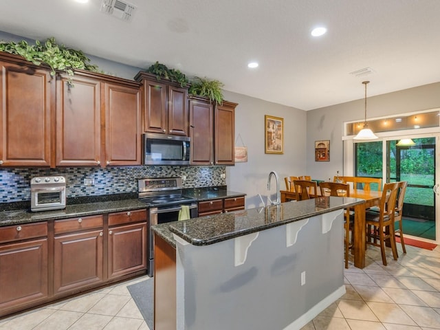 kitchen with decorative light fixtures, light tile patterned floors, visible vents, backsplash, and appliances with stainless steel finishes