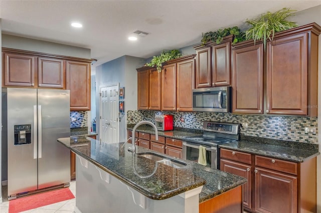 kitchen featuring a sink, stainless steel appliances, tasteful backsplash, dark stone counters, and visible vents