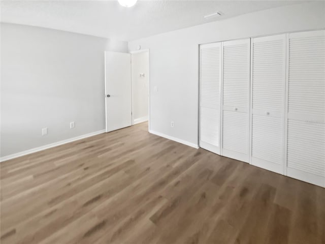 unfurnished bedroom with a closet, baseboards, and wood finished floors