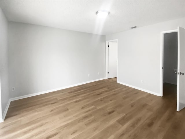 unfurnished room featuring wood finished floors, baseboards, and visible vents