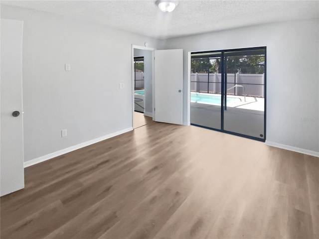 spare room featuring a textured ceiling, baseboards, and wood finished floors
