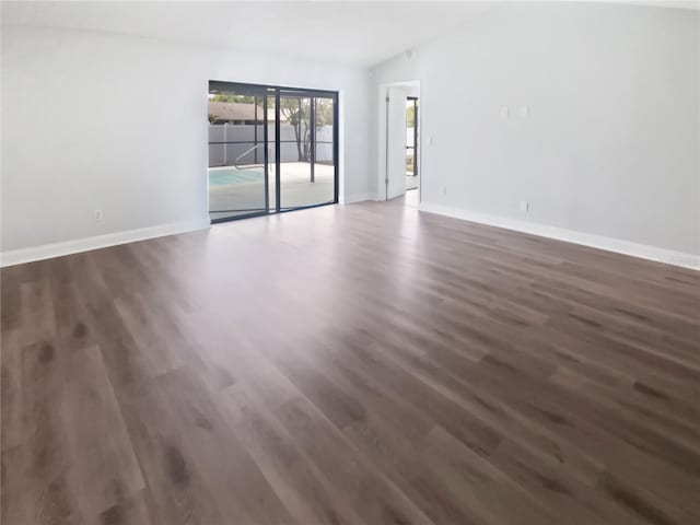 empty room with vaulted ceiling, wood finished floors, and baseboards