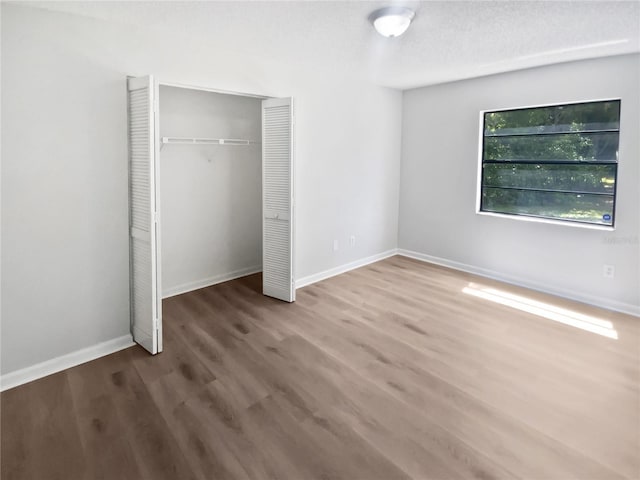 unfurnished bedroom featuring a closet, baseboards, and wood finished floors