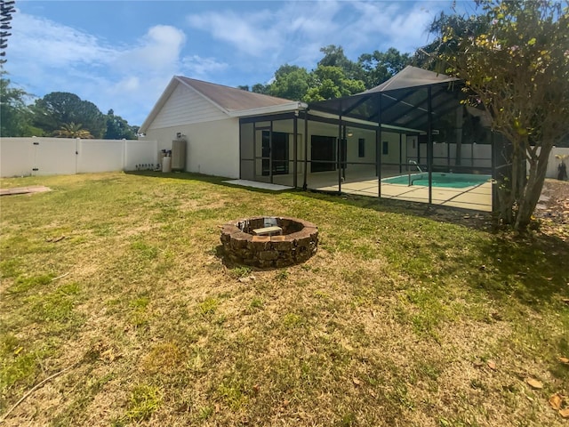 rear view of property featuring a yard, a fenced backyard, an outdoor fire pit, a lanai, and a fenced in pool