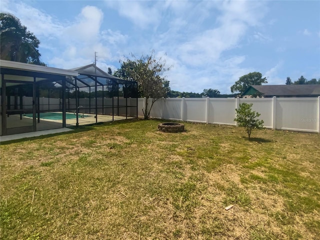 view of yard featuring a fenced backyard, a fire pit, a fenced in pool, and a lanai