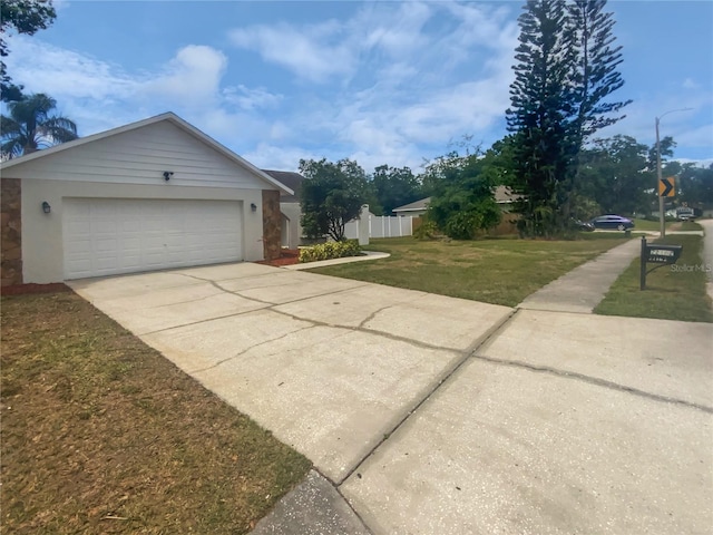 view of property exterior with fence, stucco siding, an attached garage, concrete driveway, and a lawn