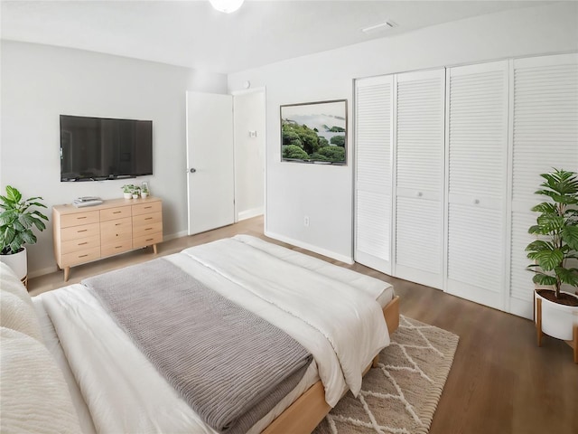 bedroom with baseboards, wood finished floors, and a closet