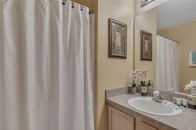 full bath with a textured wall and vanity