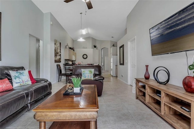 living room featuring arched walkways, baseboards, lofted ceiling, ceiling fan, and light tile patterned floors