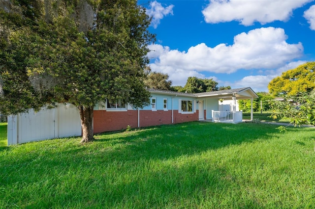 back of property featuring brick siding, a porch, fence, and a lawn