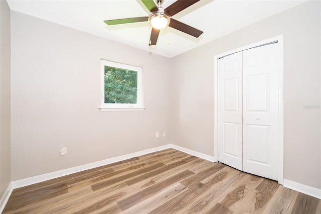 unfurnished bedroom featuring light wood-style floors, a closet, baseboards, and ceiling fan