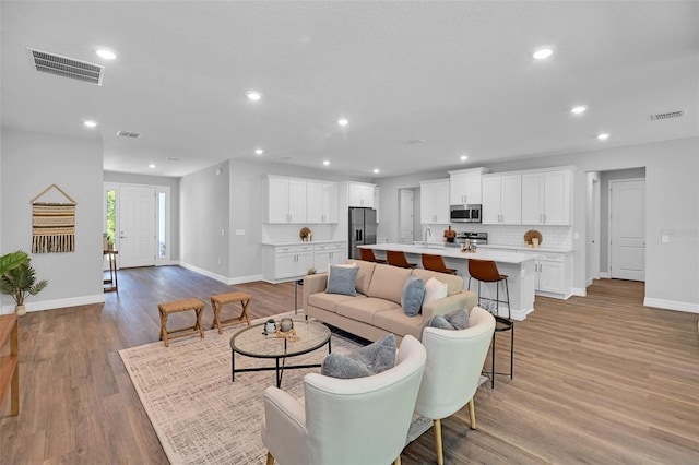 living area with light wood-type flooring, baseboards, visible vents, and recessed lighting