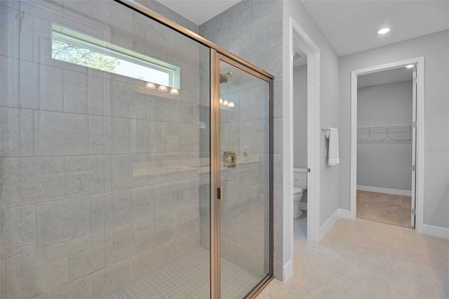 full bathroom with toilet, a walk in closet, baseboards, and a stall shower