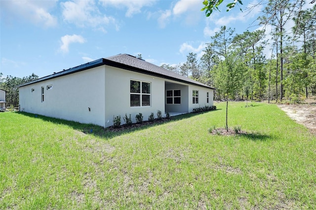 rear view of property with a yard and stucco siding
