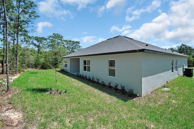 view of property exterior featuring roof with shingles, stucco siding, cooling unit, and a lawn