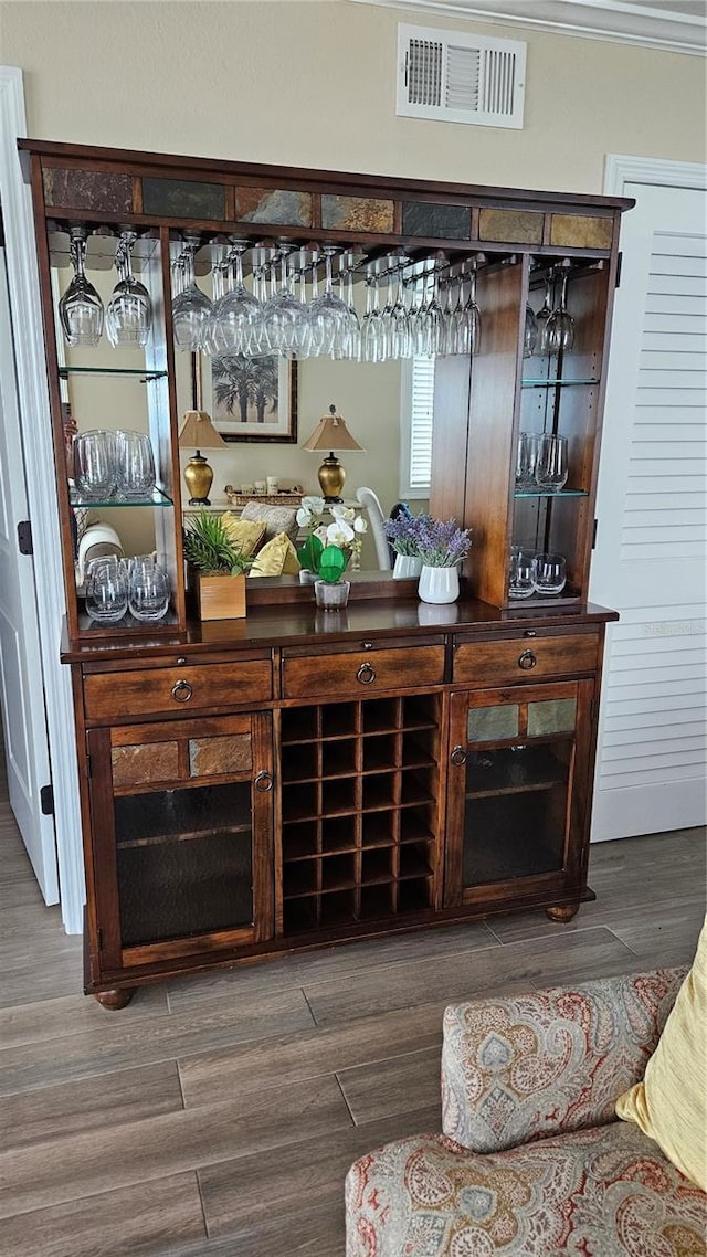 bar with crown molding, visible vents, a bar, and wood finished floors