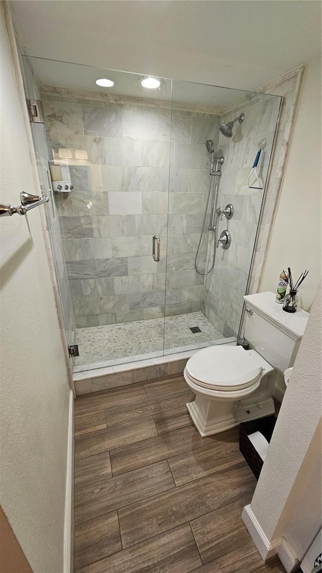 full bath with toilet, recessed lighting, wood finished floors, and a stall shower
