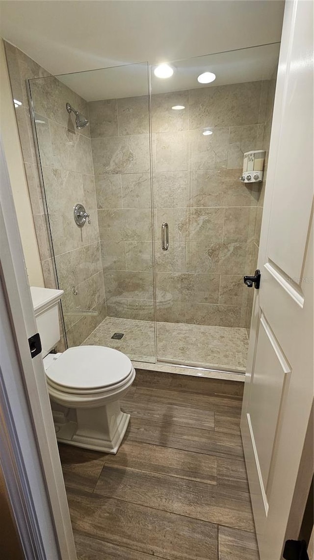 bathroom featuring recessed lighting, a shower stall, toilet, and wood finished floors