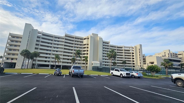 view of building exterior featuring fence and uncovered parking