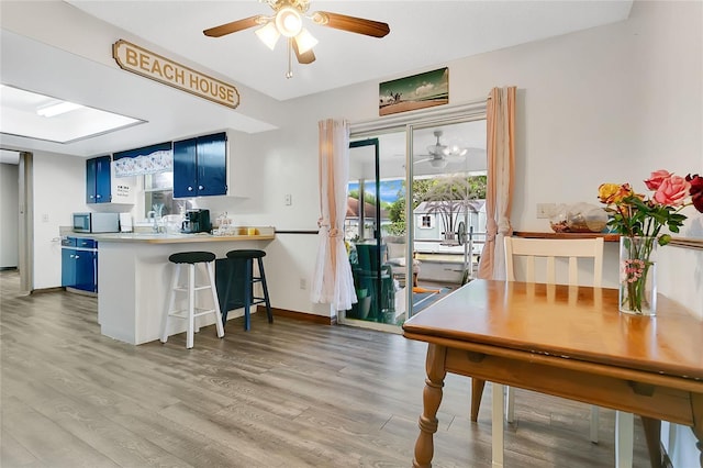 432 Taylorville St, Deltona, FL 32725 - kitchen featuring stainless steel microwave, ceiling fan, light wood finished floors, a kitchen bar, and blue cabinetry