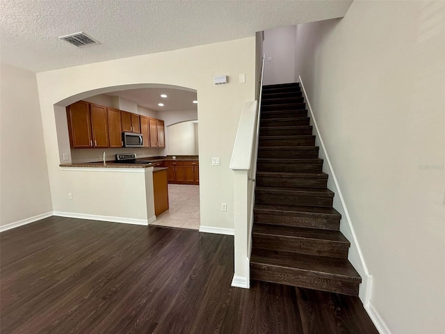 8271 Maritime Flag St Unit 125, Windermere, FL 34786 - stairs featuring arched walkways, a textured ceiling, visible vents, wood finished floors, and baseboards