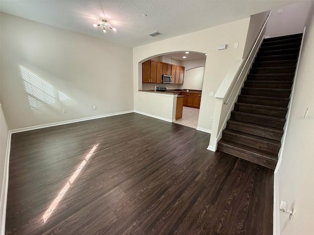 8271 Maritime Flag St Unit 125, Windermere, FL 34786 - unfurnished living room featuring dark wood-style flooring, baseboards, stairway, visible vents, and arched walkways