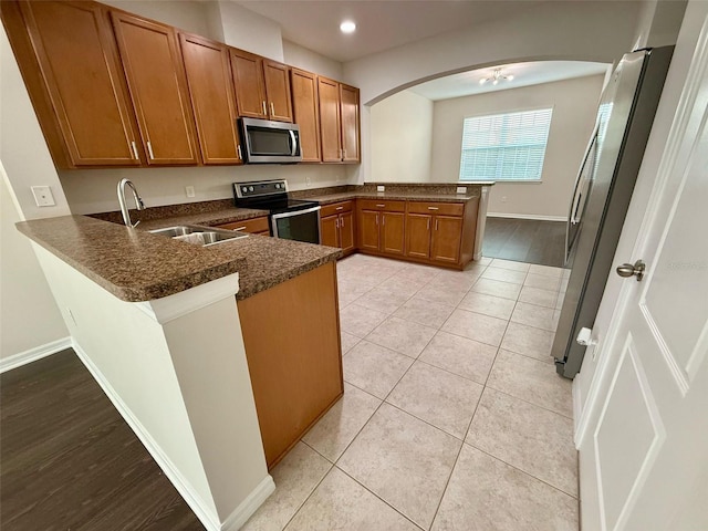 8271 Maritime Flag St Unit 125, Windermere, FL 34786 - kitchen featuring a peninsula, brown cabinets, stainless steel appliances, arched walkways, and a sink