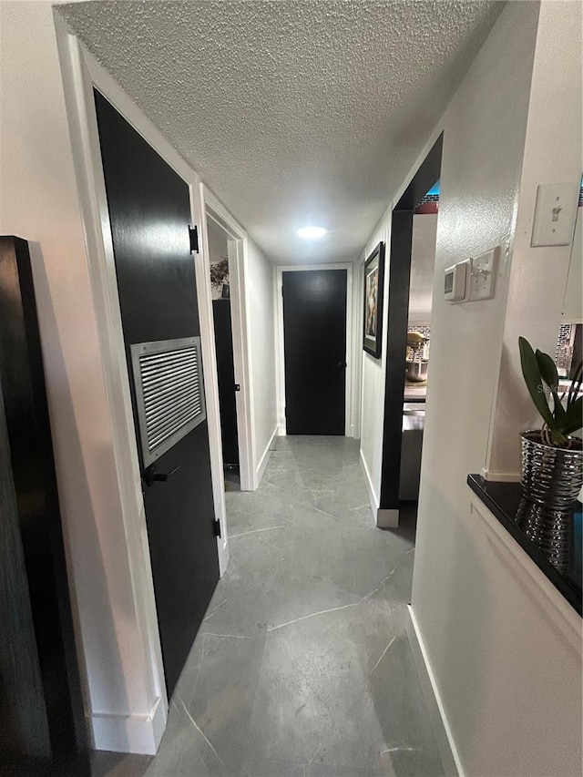 hall featuring baseboards and a textured ceiling
