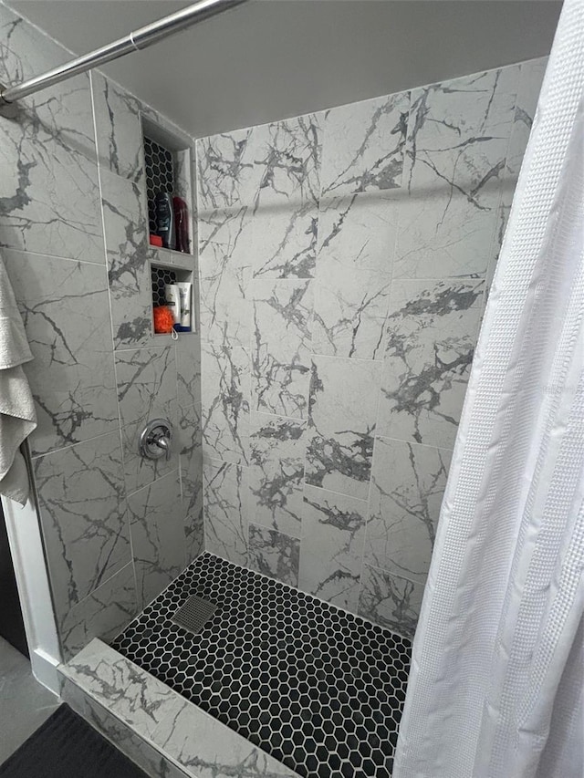 bathroom with tiled shower and marble finish floor