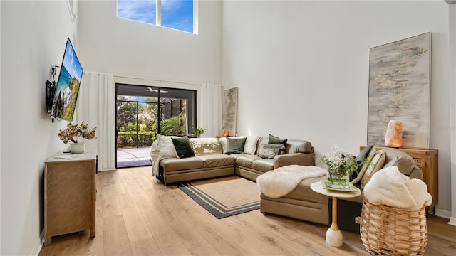 living room featuring baseboards, a towering ceiling, and wood finished floors