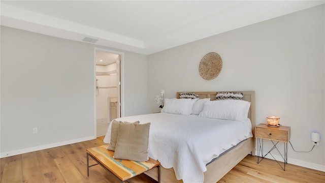 bedroom featuring baseboards, visible vents, light wood-style flooring, and ensuite bathroom