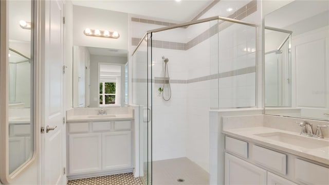 bathroom with two vanities, a shower stall, and a sink
