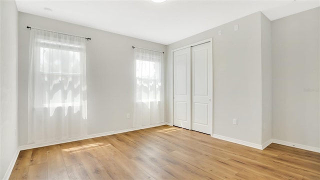 unfurnished bedroom with a closet, baseboards, and light wood-style floors