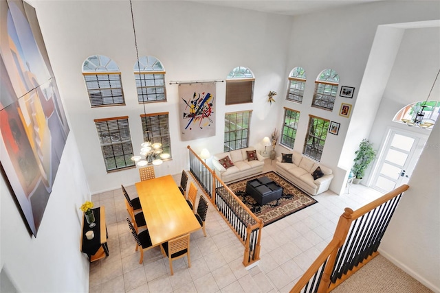 living room with a chandelier, a high ceiling, baseboards, and a healthy amount of sunlight