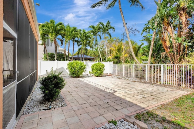 view of patio featuring a fenced backyard and glass enclosure