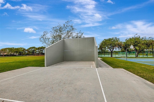 surrounding community with uncovered parking, a yard, and community basketball court