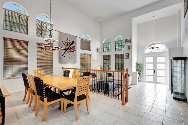 dining space featuring french doors, a high ceiling, an inviting chandelier, and light tile patterned floors